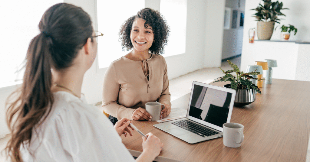 Professional HR team members discussing self-storage staffing solutions in a bright, modern office with a laptop and coffee